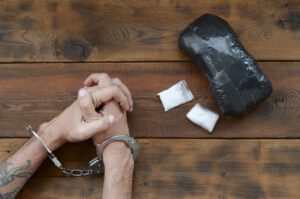 Drug Trafficker Arrested With Their Heroin Packages. Police Arrest Drug Dealer With Handcuffs And Narcotic Packages On Wooden Table