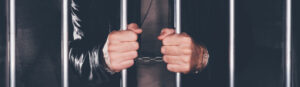 Handcuffed Man Behind Prison Bars